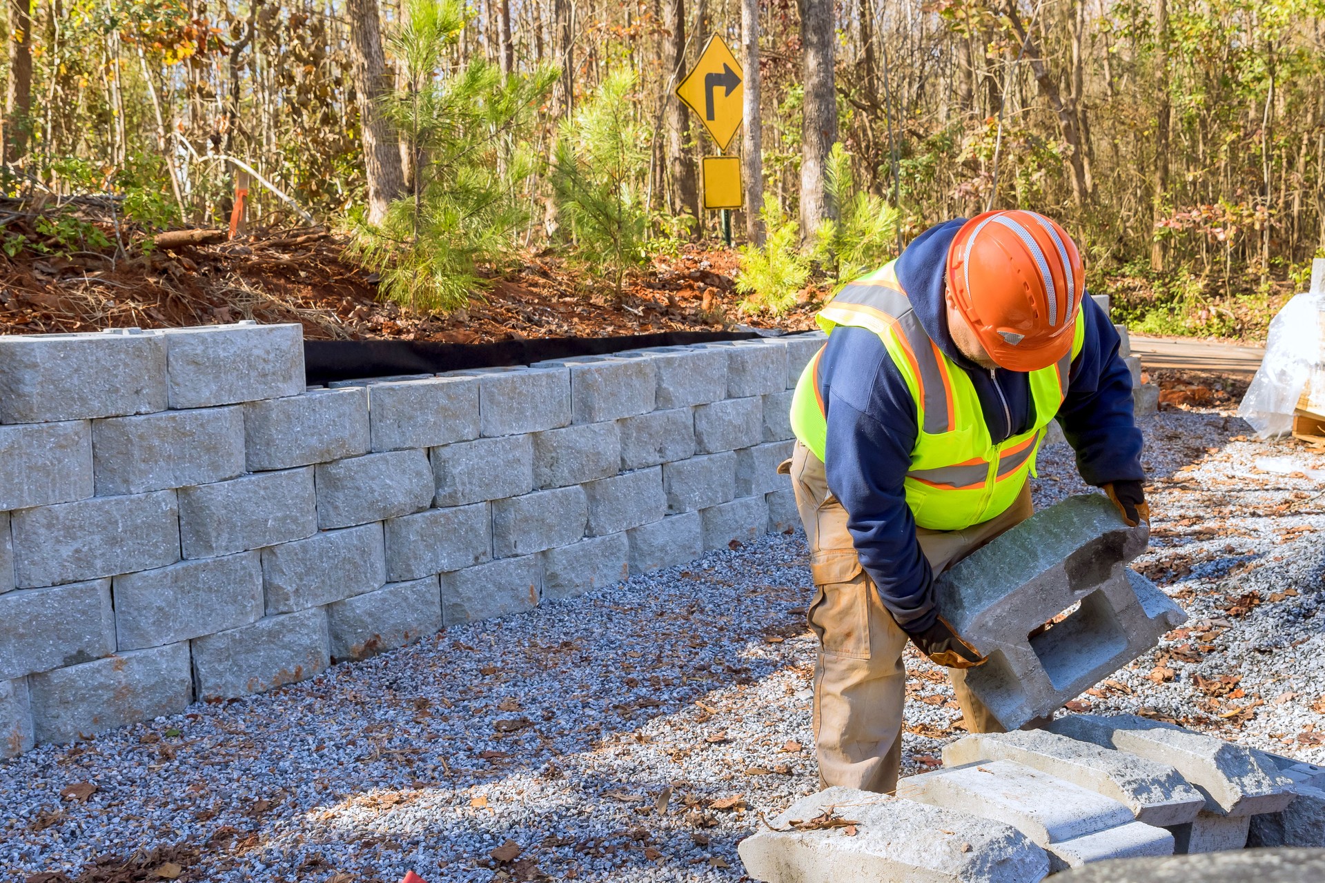 Construction worker is currently working on building retaining wall while constructing wall a retaining in new property.